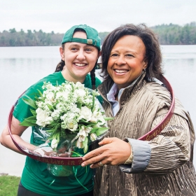 Laurel Wills ’17 and President Paula Johnson pose inside Laurel's hooprolling hoop as Laurel holds a bouquet of flowers.