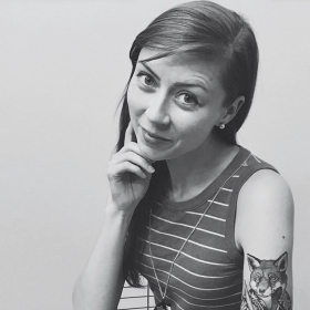 A black-and-white photo of author reveals her upper-arm tattoo of a fox holding a pen. 
