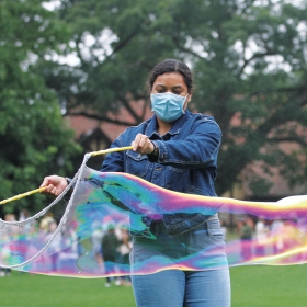 A photo shows a student creating an enormous, iridescent bubble.