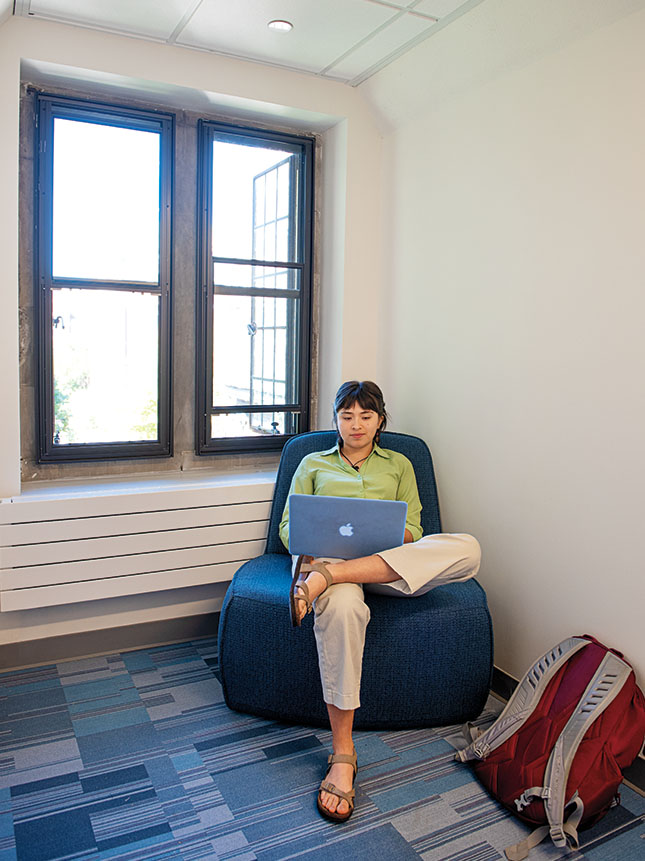 A student relaxes in a new chair in a gabled nook