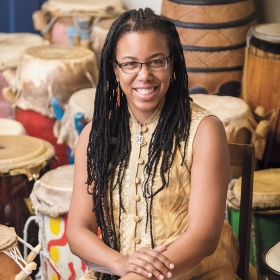 Kera Washington '93 sits among the African drums that Yanvalou members play.