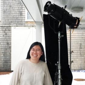 Cathy Ye ’19 stands next to professional lighting equipment.