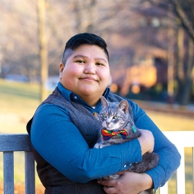 A portrait of AJ Guerrero, Wellesley’s coordinator for LGBTQ+ programs and services, holding her cat
