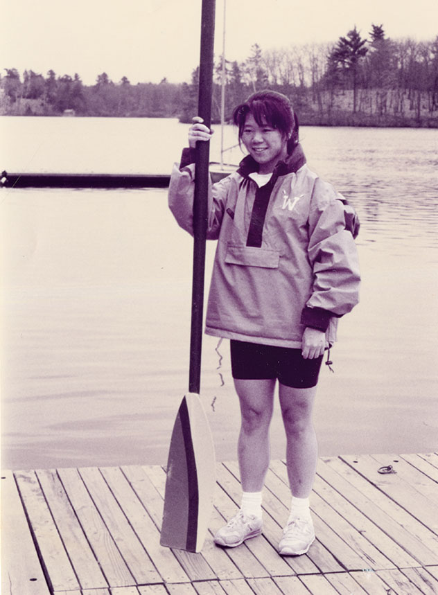 A student stands on a dock holding an oar
