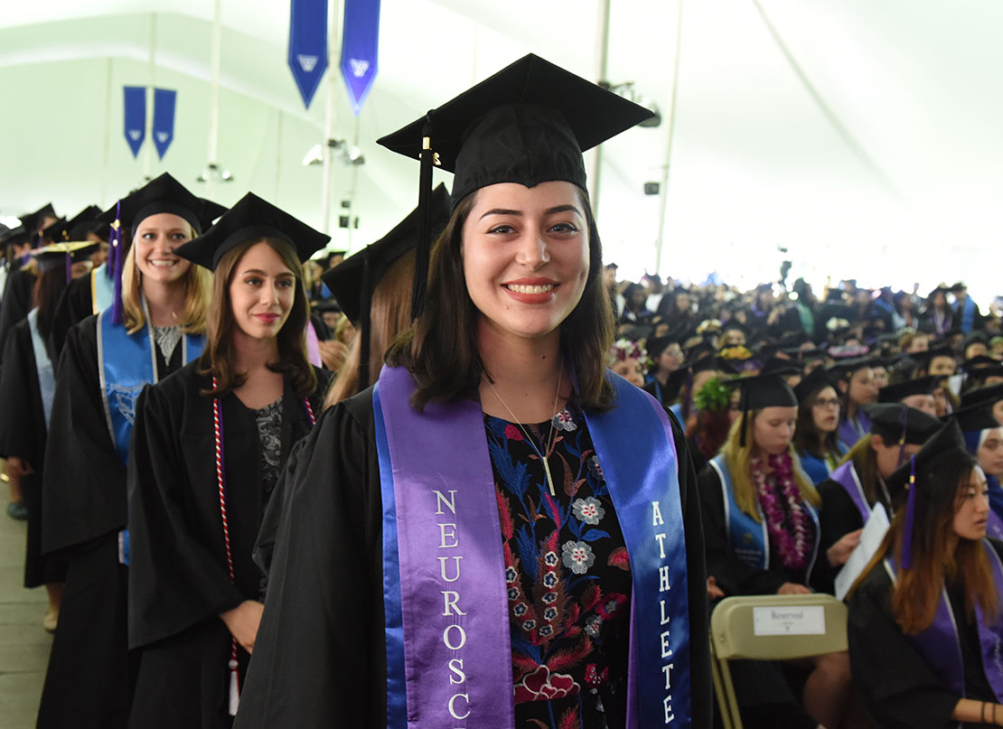 A photo of a member of the purple class of 2018 as she processes into the tent at Commencement.
