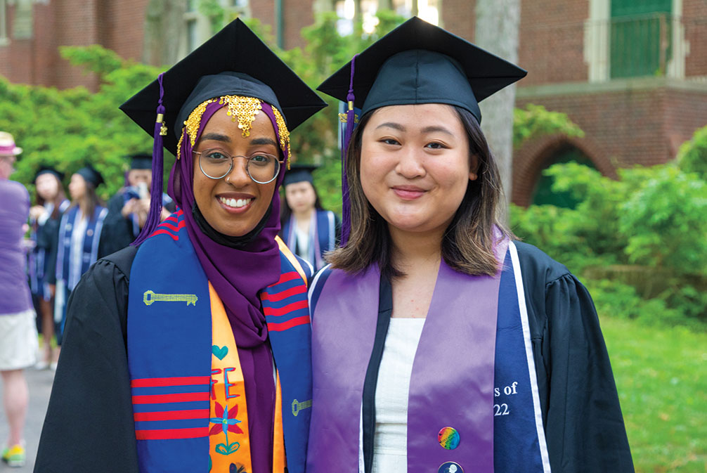 Two graduates smile after the ceremony.