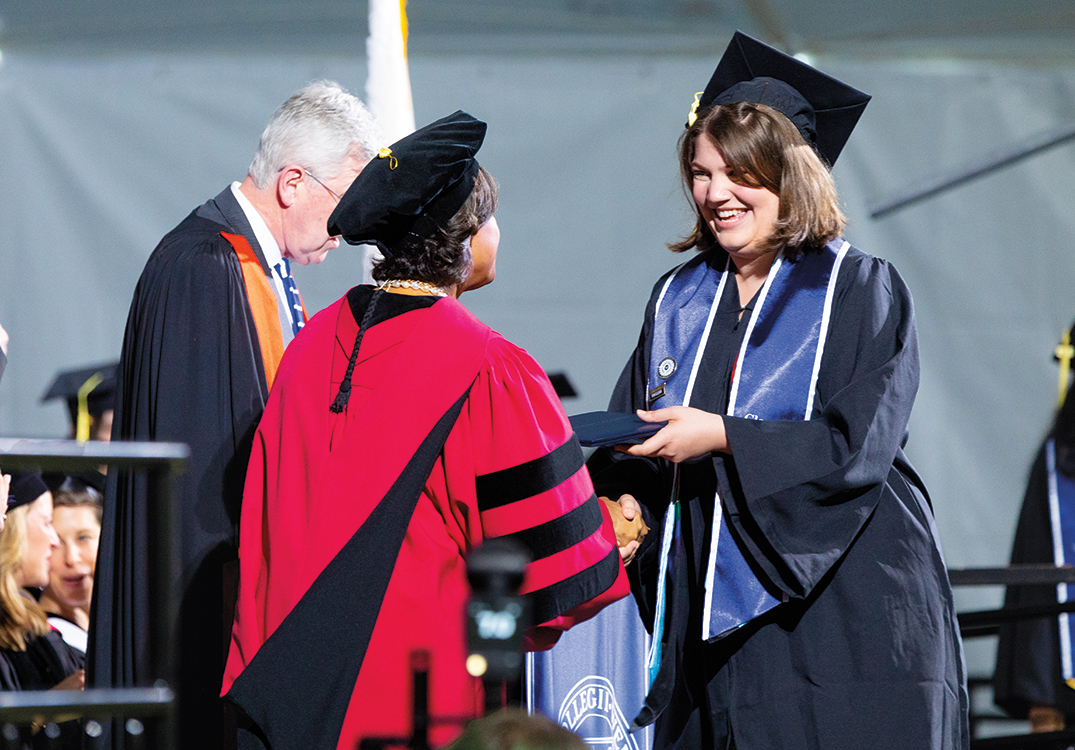 A graduate shakes hands with President Paula Johnson.