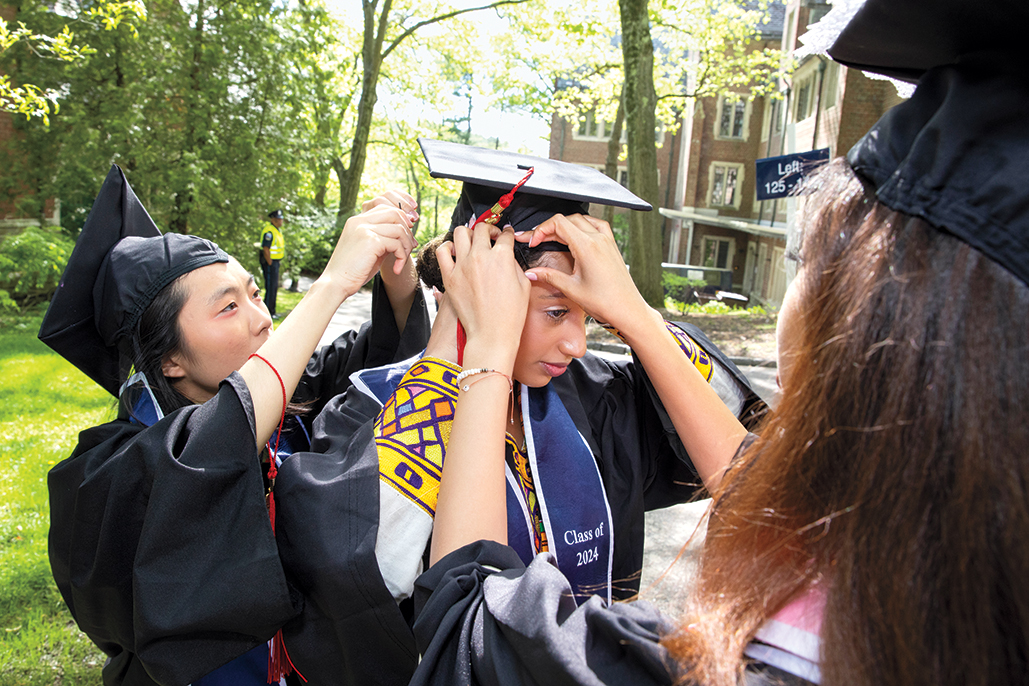 A senior gets help adjusting a mortar board before the ceremony.