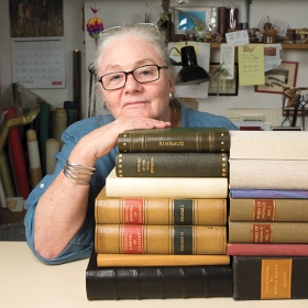A photo portrait shows Betsy Palmer Eldridge  with her chin propped on a pile of antique books.