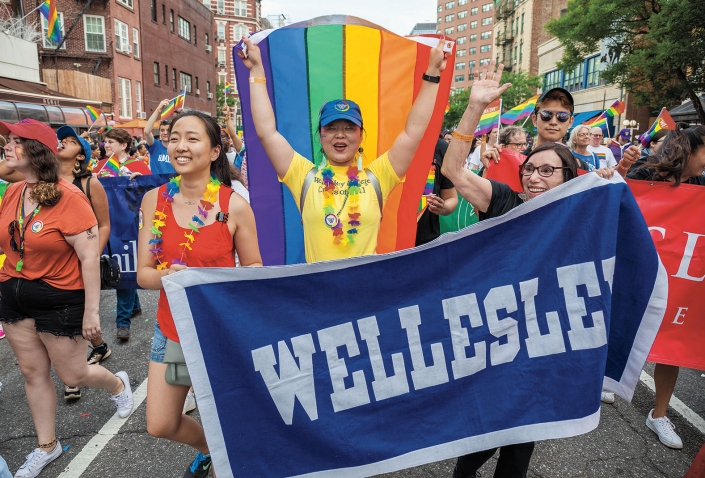 A photo shows Wellesley women marching with a rainbow flag and the Wellesley banner at the New York City Pride Parade in June.