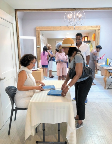 A photo shows Cheryl Finley ’86 signing books at the Featherstone Center for the Arts in Oak Bluffs, Mass.