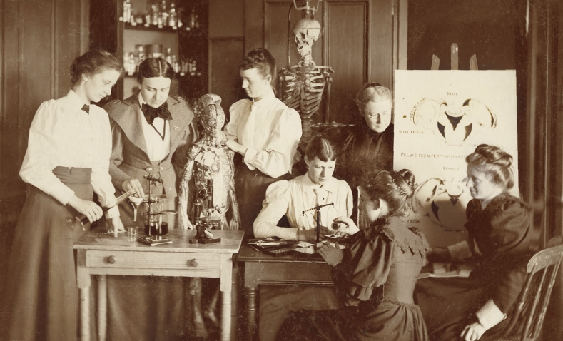 A photo from the early days of Wellesley of students studying scientific models in College Hall.