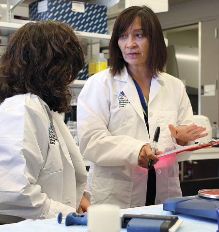 A photo shows cancer researcher Nina Bhardwaj '75 talking with a colleague at Mt. Sinai Hospital in New York City.