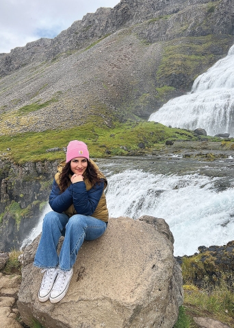 In a photo, Julz Vargas ’24 sits on a boulder near a waterfall in Iceland