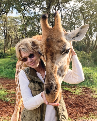 A photo shows Susan Reno Myers '74 embracing a giraffe.