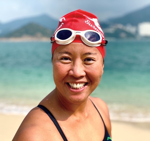A photo shows Edie Hu '97 on a beach in Hong Kong, wearing a bright red swim cap.