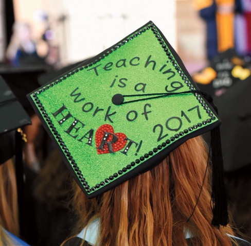 A student's tam is decorated with "Teaching is a work of heart! 2017"