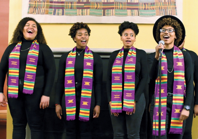 A photo shows members of the Harambee Singers, wearing kente-cloth stoles, performing.