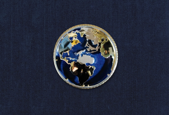 Secretary Albright's pin depicts a globe with the continents in silver and gold on a blue background. 