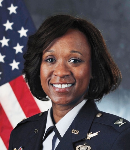 An official portrait of Kayle Stevens '99 shows her in uniform and has an American flag in the background.