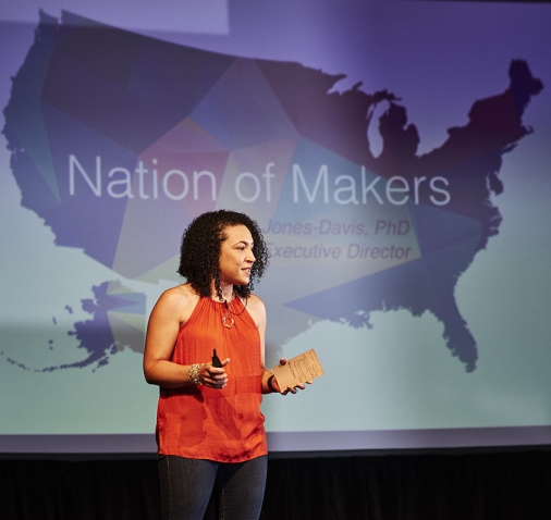 A photo shows Dorothy Jones-Davis ’98 speaking in front of a large map of the United States with the words "Nation of Makers" emblazoned across it.