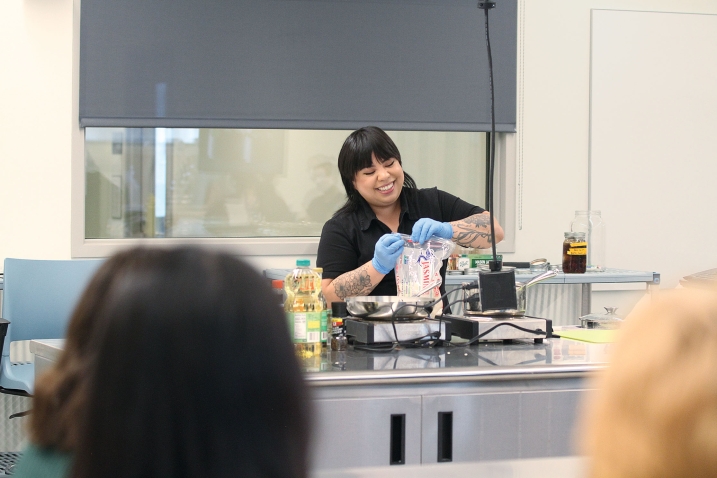 Photo of Bettina Makalintal opening a bag of rice as part of a cooking demonstration 