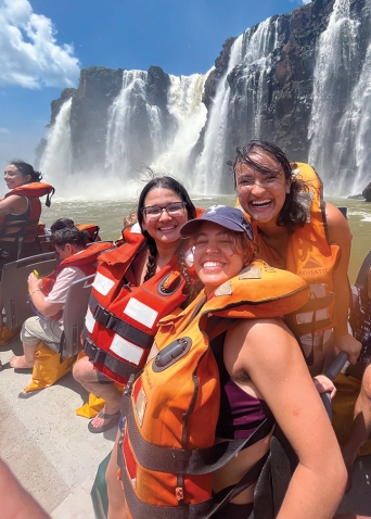 A photo of Ana Julia Daza Walter ’24 at Iguazu Falls with friends, smiling and wearing life preservers