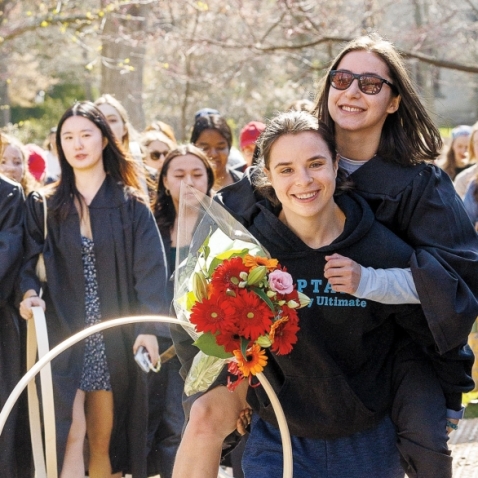 A photo of Emma Feldman ’24, this year’s Hooprolling champion, being carried toward Lake Waban.