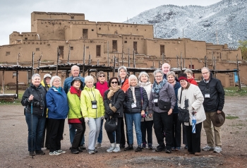 A photo depicts members of the class of '67 in fromt of a pueblo in Taos, New Mexico.