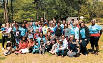 A photo of a large group of alumnae gathered in a park to celebrate the Atlanta Wellesley Club's 80th birthday. 