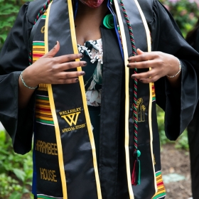 A student adjusts Harambee House and Africana studies stoles before commencement