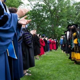 Faculty applaud as students process during commencement