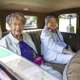 Two alums riding in a an antique car at the parade