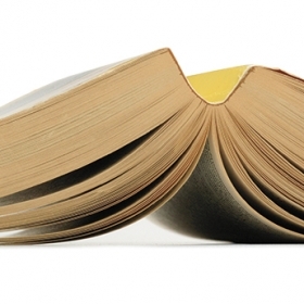 A photo shows an open paperback book, splayed face down.