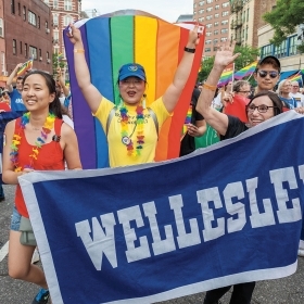 A photo shows Wellesley women marching with a rainbow flag and the Wellesley banner at the New York City Pride Parade in June.