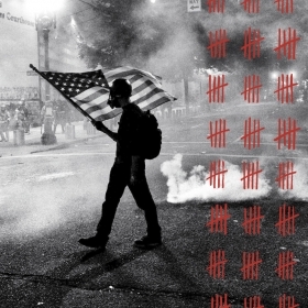 A black-and-white photos depicts a Black Lives Matter protester carrying an American flag as tear gas fills the air outside the Mark O. Hatfield United States Courthouse in Portland, Ore., on July 21. 