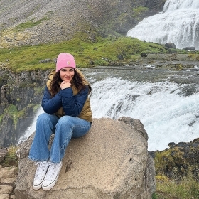 In a photo, Julz Vargas ’24 sits on a boulder near a waterfall in Iceland