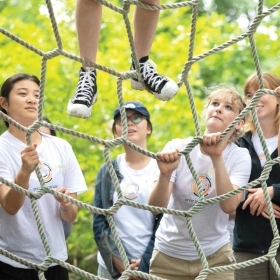 Students climb a rope structure during a trust exercise.