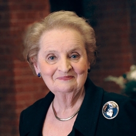 A photo portrait of Madeleine Korbel Albright wearing a pin that depicts the Earth
