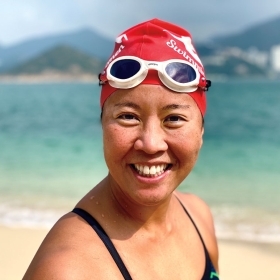A photo shows Edie Hu '97 on a beach in Hong Kong, wearing a bright red swim cap.