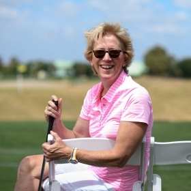 A photo of Leslie Andrews ’82,golf club in hand, on the course at Nehoiden.