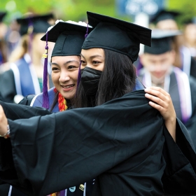 Two students take a selfie together before commencement