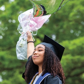 A student poses with balloons after commencement