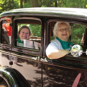 Alumnae ride in antique cars in the parade