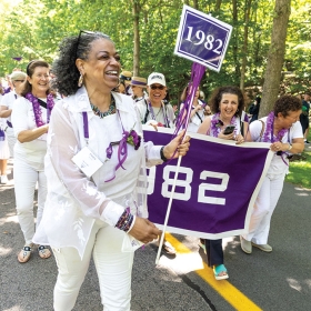 The purple class of 1982 marches and cheers with their banner