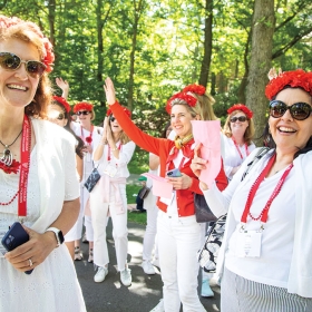 Members of a red class wearing red floral crowns cheer at the parade