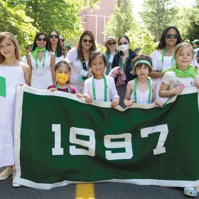 The green class of 1997 and some children pose with their banner