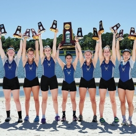 The Wellesley crew team holds their trophies in the air.