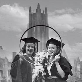 A photo of two 1945 alums holding up their hoops after the race. The winner has a bridal veil attached to her mortar board.