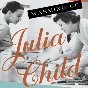 The cover of Warming Up Julia Child depicts the chef preparing a dish as another chef looks on.